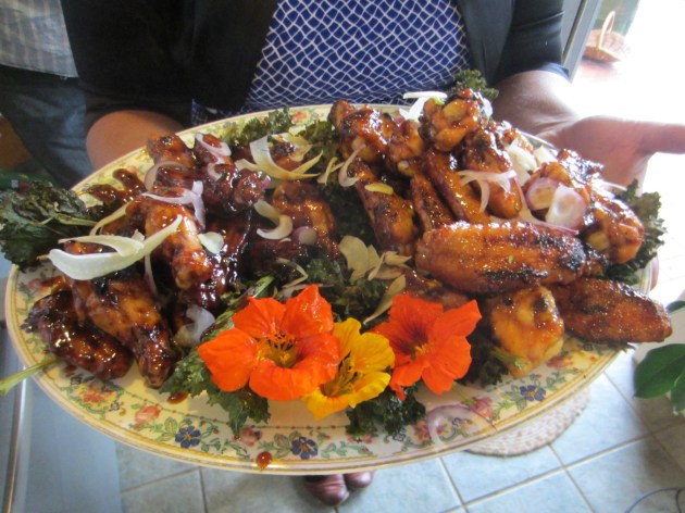 Grilled chicken wings tossed with Asian inspired sweet and spicy sauces, served with nasturtium flowers on a bed of kale chips.